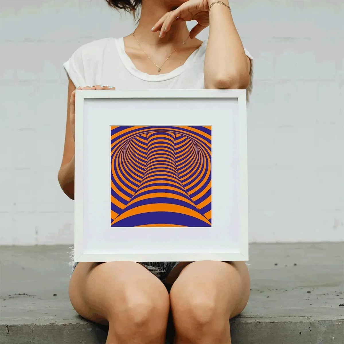 Person holding a framed abstract artwork with orange and blue patterns.