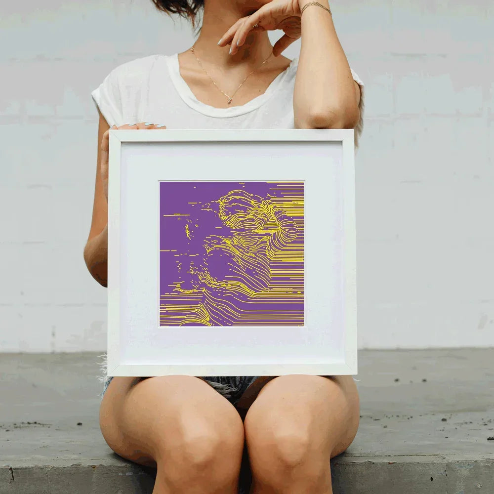 Person holding a framed abstract art print with purple and yellow design.