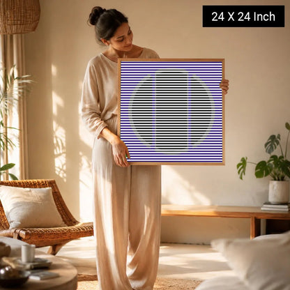 A woman holds a 24x24 inch therapeutic wall art print featuring bold striped patterns in purple and black, designed for welln