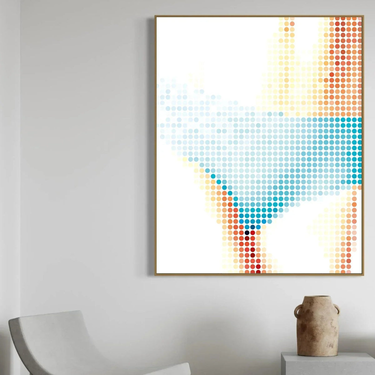 Abstract dot artwork in a gold frame on a gray wall with a chair and vase in the foreground.