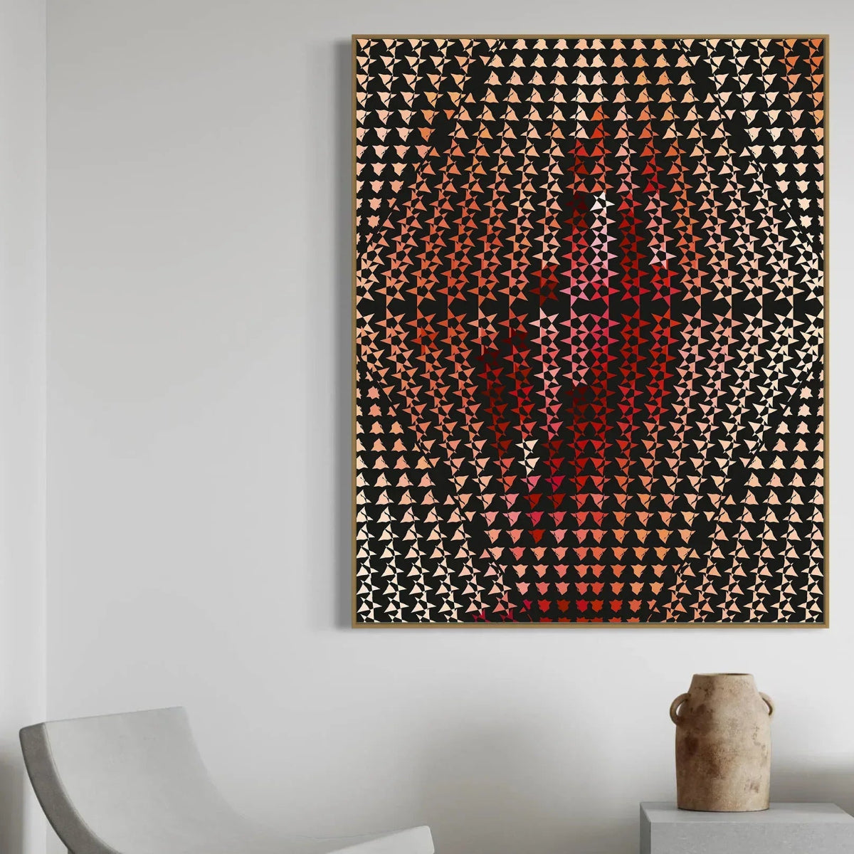 Abstract art piece with geometric patterns on a white wall, featuring a chair and vase in the foreground.