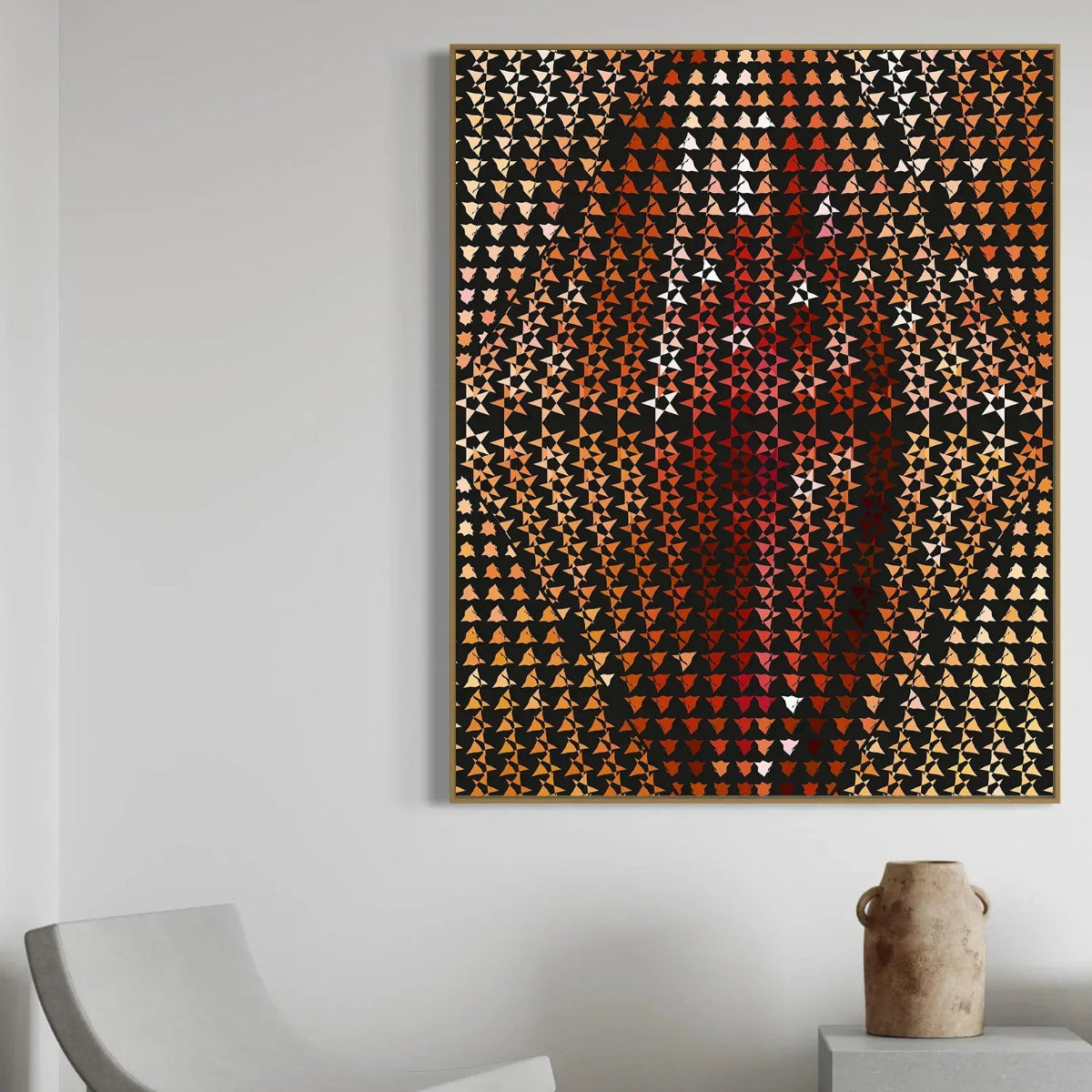 Abstract art piece with geometric pattern on a white wall above a chair and small table.