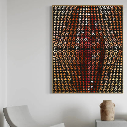 Abstract art piece with geometric pattern on a white wall above a chair and small table.