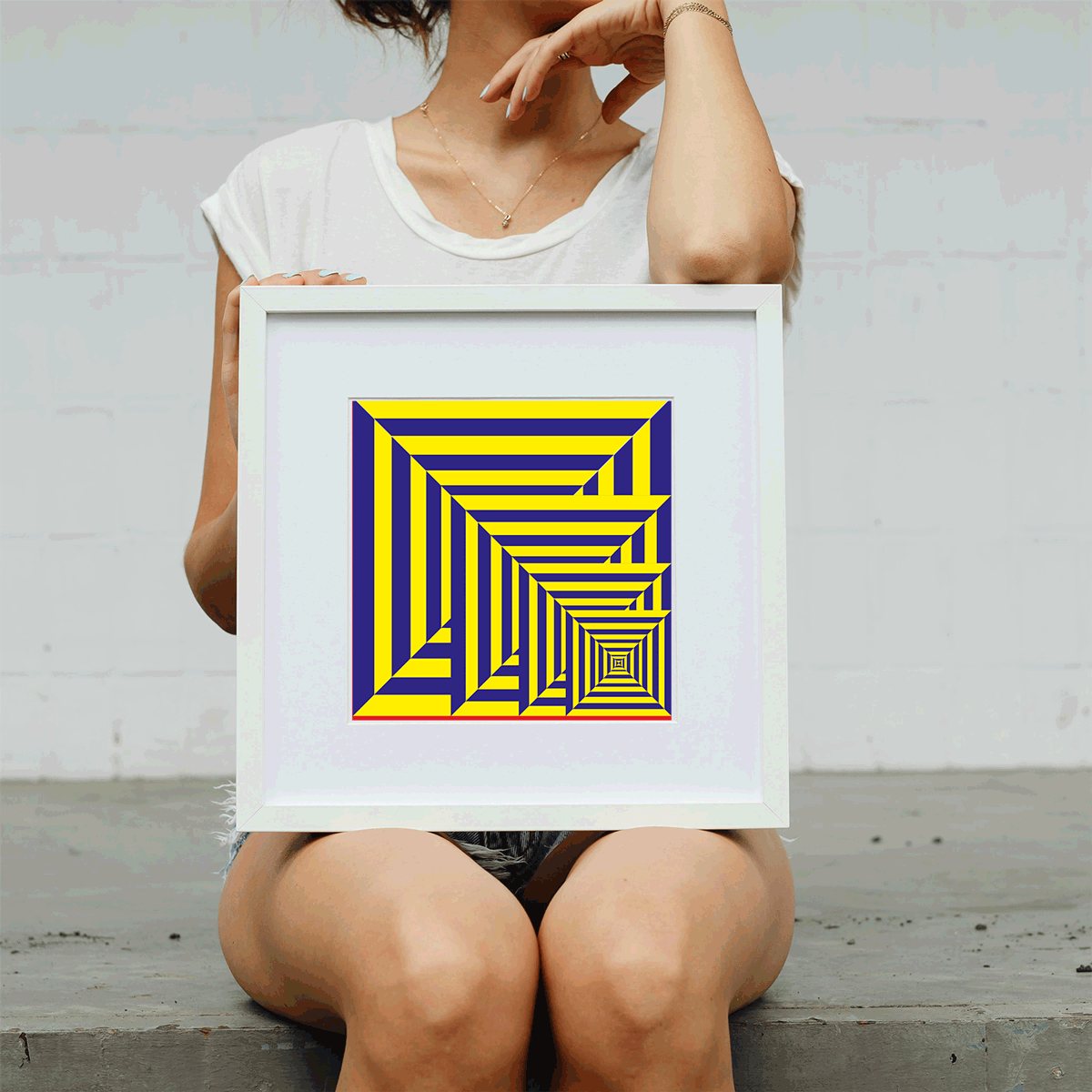 Person holding a framed yellow and blue geometric art print against a plain background