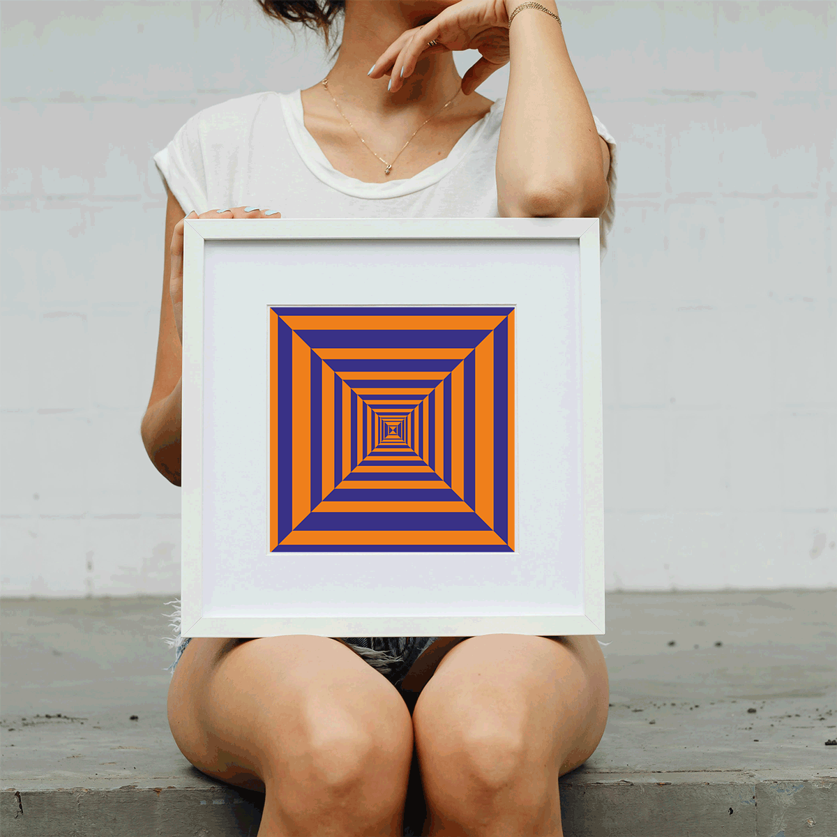 Person holding a framed geometric art piece with a white background