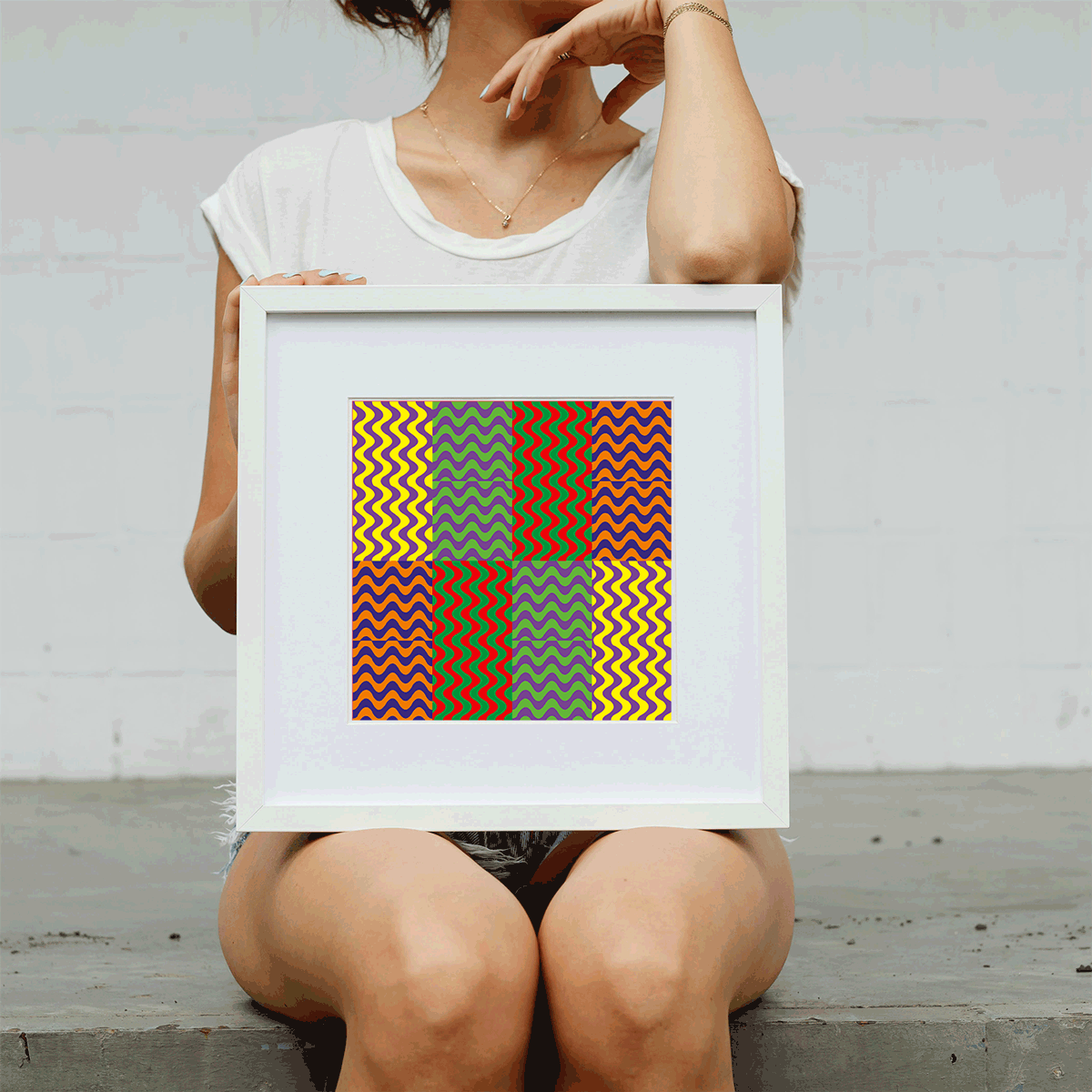 Person holding a framed colorful geometric art piece against a plain background