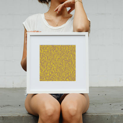 Person holding a framed artwork with a yellow pattern against a plain background